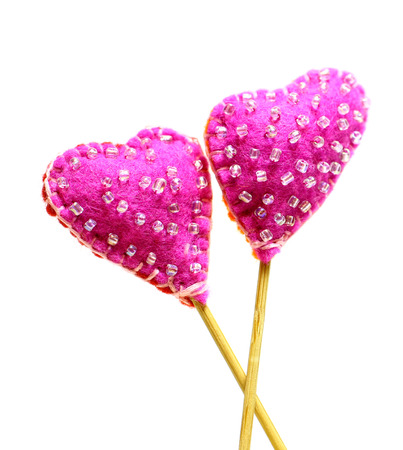 Decorative hand made two hearts isolated on white background. Sewed from a felt and decorated with beads. Beautiful congratulation card background for St. Valentine`s day. Copyspace.の写真素材