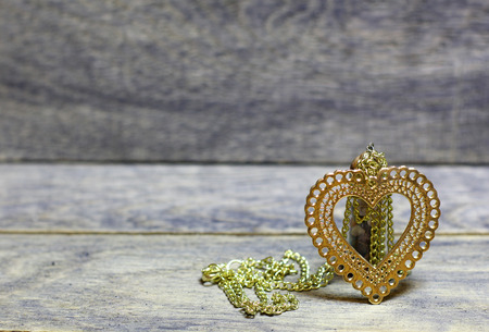 Golden heart on a chain and colored stones, minerals in the bottle on wooden background. Beautiful congratulation card background for St. Valentine`s day. Copyspace.の写真素材