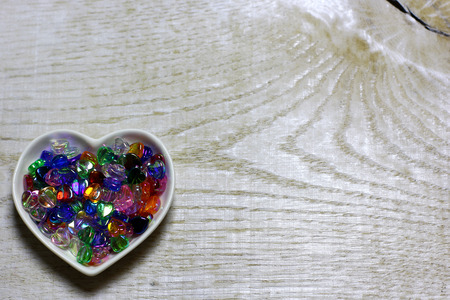 Colorful glass beads hearts on wooden background. Love card for Valentine's day. Concept with big copyspase for hand crafts or DIY illustration.の写真素材