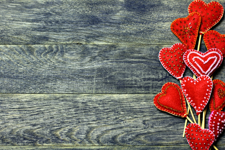 Right frame border of Handmade felt red color hearts on dark old wooden background. Love card for Valentine's day. Concept with big copyspase for hand crafts or DIY illustration.の写真素材