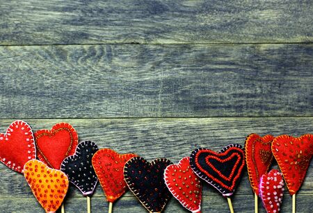 Bottom frame border of Handmade felt colorful hearts on dark old wooden background. Love card for Valentine's day. Concept with big copyspase for hand crafts or DIY illustration.の写真素材