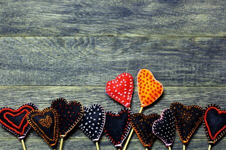 Bottom frame border of Handmade felt hearts on dark old wooden background. Two hearts different colors. Love card for Valentine's day. Concept with big copyspase for hand crafts or DIY illustration.の写真素材