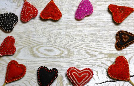Frame border of Handmade felt hearts on light wooden background. Love card for Valentine's day. Concept with big copyspase for hand crafts or DIY illustration.の写真素材