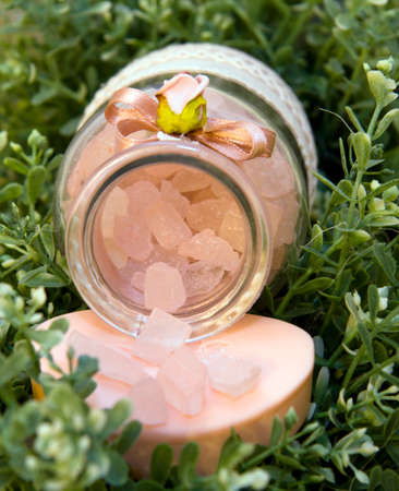 pink bath salt lies on the green leaves