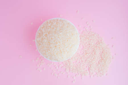 uncooked rice groats on a pink background