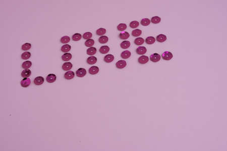 word love from sequins on a pink backgroundの写真素材
