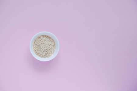 white sesame seeds, in a small cup, on a pink backgroundの写真素材