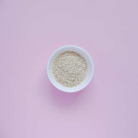 white sesame seeds, in a small cup, on a pink backgroundの写真素材