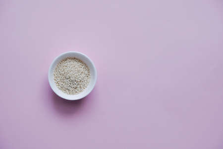 white sesame seeds, in a small cup, on a pink backgroundの写真素材