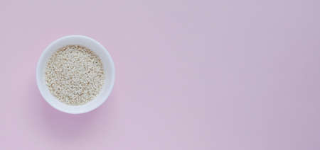 white sesame seeds, in a small cup, on a pink backgroundの写真素材