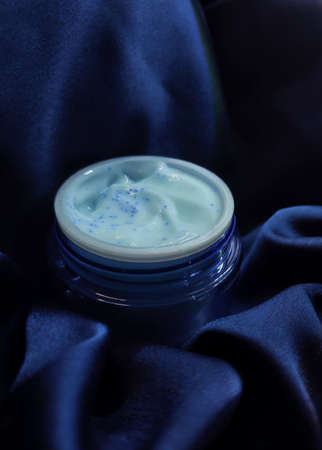 cosmetic cream on a background of blue satin fabricの写真素材