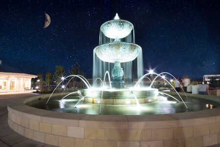 Long exposure of fountain with moon in background at night