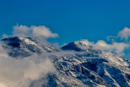 High mountain peaks above the clouds with snow and a blue sky.の写真素材