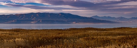 Panorama of the mountains, lake and dry grass at dawn on a hazy morning.の写真素材