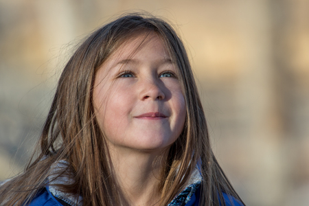 Young, cute girl looks to the skies on a bright, sunny, but cold, day.の写真素材