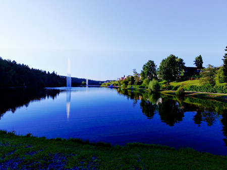 Beautiful pond and fountain in a park with green vegetationの写真素材