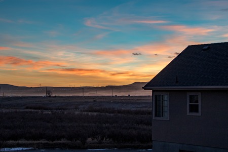 Stunningly colorful sunset or sunrise looking from the back decking of a modern homeの写真素材