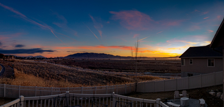 Stunningly colorful sunset or sunrise looking from the back decking of a modern homeの写真素材