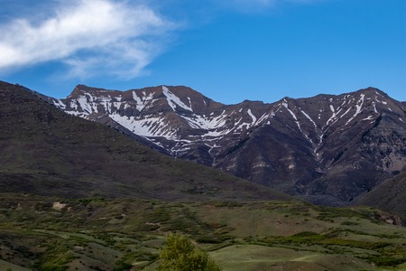 Beautiful landscape of snow on the mountains with a clear sky and some cloudsの写真素材