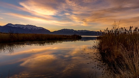 Golden morning sunrise colors reflecting off the lake with the snow-capped Rocky Mountains in the backgroundの写真素材