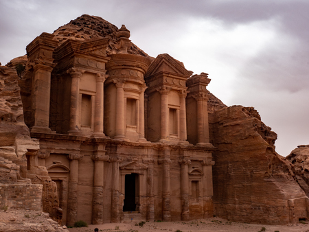 Sunlight breaks through the clouds and lights up the front of the Monestary at Petra Jordanの写真素材