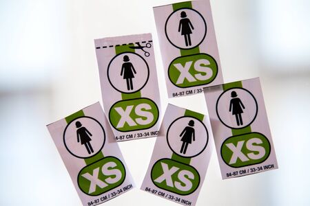 Five XS women labels placed on a window glass with a white blurred background.の写真素材