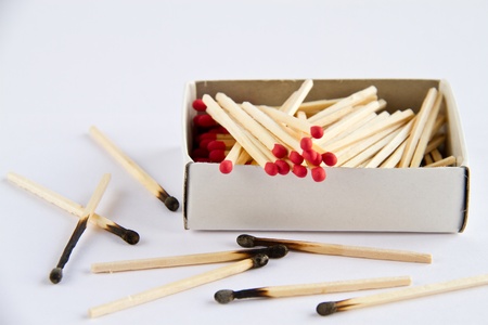 Box of matches and burned matches over white.