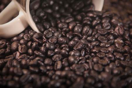 Coffee beans close up, coming out of a white cup.