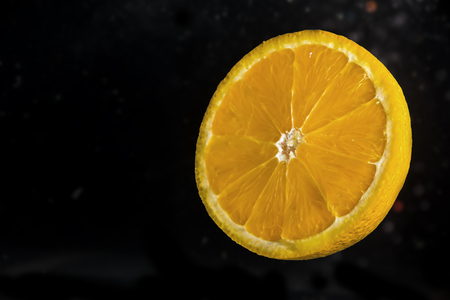 Slice of lemon on black background submerged in water with bubblesの写真素材