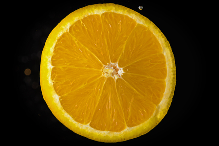 Slice of lemon on black background submerged in water with bubblesの写真素材