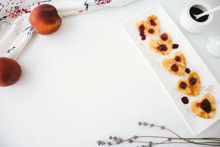 Composition of american homemade pancakes with jam and peaches on white wood background.