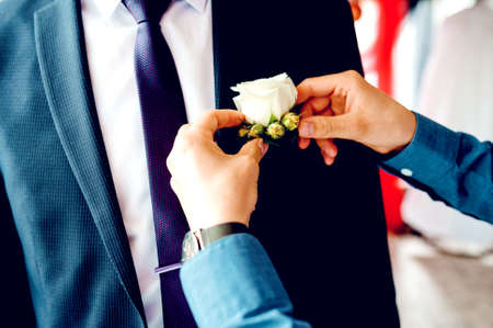 Best man helping groom getting ready for wedding. Wedding day.