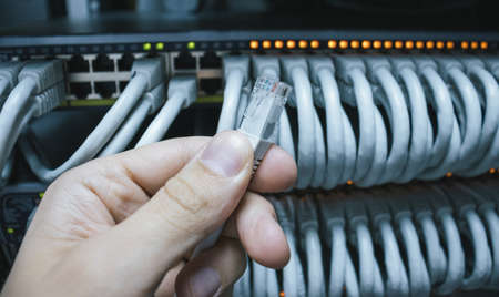 Man holding an cable ready for connection into the network switch.の写真素材