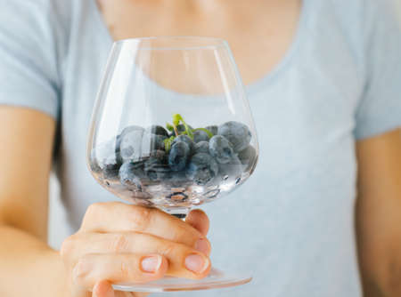 Closeup of woman holding a glass with fresh blueberries.の写真素材