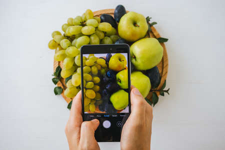 Person taking photo of fresh mixed fruits on bright background.の写真素材