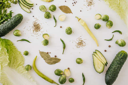 Top view of green mixed vegetables on white wooden background.