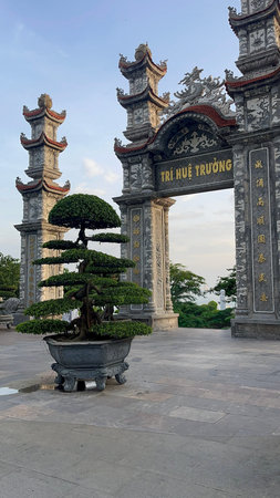 Detailed view of the carved stone entrance gate with layered towers and golden inscriptions. A...