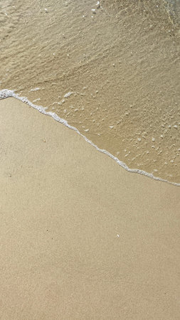 Small ocean wave washing clean sand on a tropical beach creating natural minimal background.