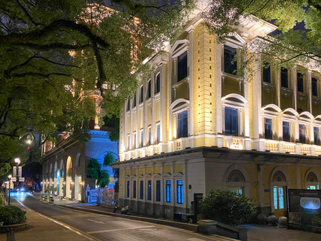 Elegant historic buildings with classical architecture illuminated at night along a quiet city...