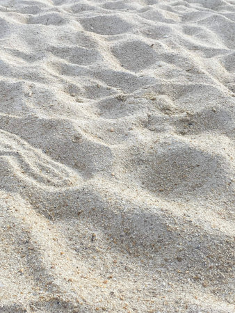 Close view of natural ripple patterns and texture on light sandy beach surface.