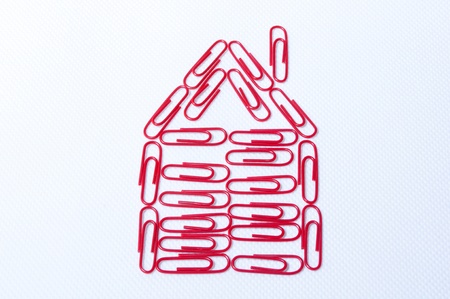 desing a house with red paper clips on the white backgraundの写真素材