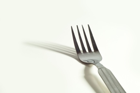 metallic fork and her shadow on the white backgroundの写真素材