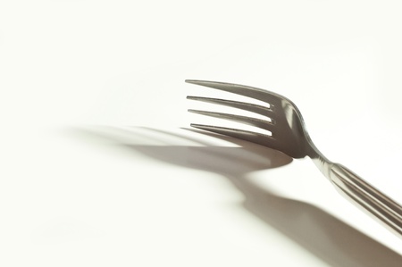 metallic fork and her shadow on the white backgroundの写真素材