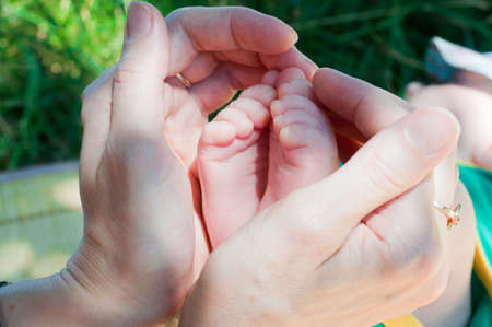 small legs of the child in hands of motherの写真素材