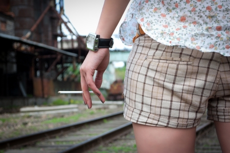 hips of the girl in checkered shorts and one hand with a cigarette close upの写真素材