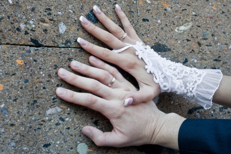 hands of the newly-married couple with rings on a stone wallの写真素材