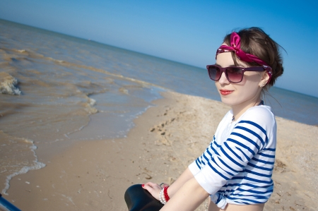 the beautiful girl with bicycle on walk at the sea against the blue skyの写真素材