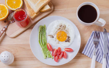Healthy breakfast with fried egg toasts and strawberry jam on wooden tableの写真素材
