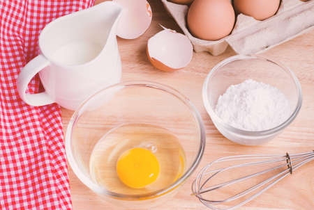 Cookies ingredients. Bowl flour eggs jar of milk eggbeater eggshells and red napkinの写真素材
