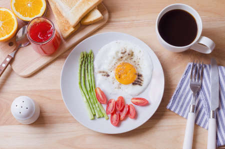 Healthy breakfast with fried egg, toasts and strawberry jam on wooden tableの写真素材